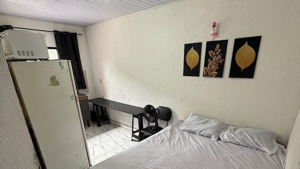A bedroom with a bed, a refrigerator, a desk, and a chair. - Ideal apartment for a couple, Serra da Cantareira. (Caieiras)