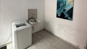 A small, clean bathroom with a washing machine, a sink, and a poster on the wall. - Ideal apartment for a couple, Serra da Cantareira. (Caieiras)