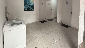 A laundry area with a washing machine, a drying rack, and a painting on the wall. - Ideal apartment for a couple, Serra da Cantareira. (Caieiras)