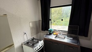 A small kitchen with a stove, sink, and window. - Ideal apartment for a couple, Serra da Cantareira. (Caieiras)