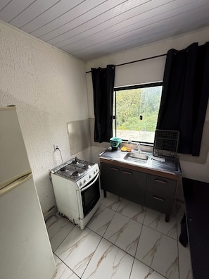 A small kitchen with a stove, sink, and window. - Ideal apartment for a couple, Serra da Cantareira. (Caieiras)
