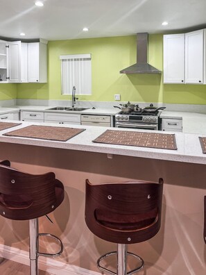 Una cocina moderna con armarios blancos, un lavamanos de acero inoxidable y una estufa a gas.
