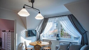 A dining area with a round table, chairs, and a television on the wall.