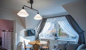 A dining area with a round table, chairs, and a television on the wall. - Apartamentów Miluchna (Zakopane)