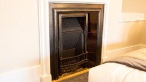 A room with a fireplace, a bed, and a white wall. - Turl Street Mitre (Oxford)