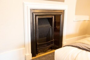 A room with a fireplace, a bed, and a white wall.