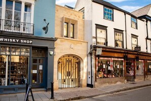 Straatbeeld met een winkel met de naam 'WHISKY SHOP' en een andere winkel met een bordje 'WALTERS'.