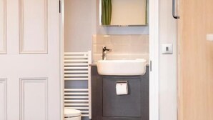 A bathroom with a toilet, sink, and mirror. - Turl Street Mitre (Oxford)