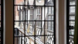 A view through a window with a grid pattern, displaying a row of buildings with traditional architecture. - Turl Street Mitre (Oxford)