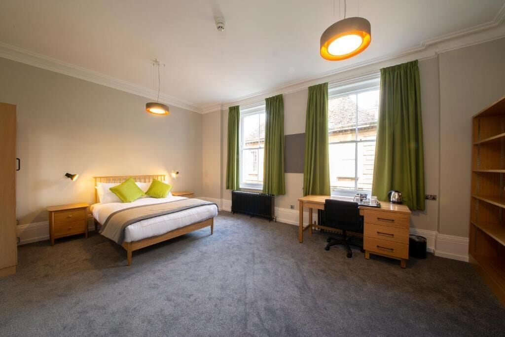 A bedroom with a bed, desk, chair, and a radiator.