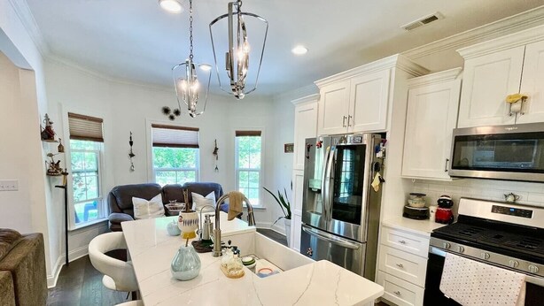 A modern kitchen with white cabinetry, a large island, stainless steel appliances, and pendant lighting. - Immaculate 4 Bedroom with Pool Table (High Point)