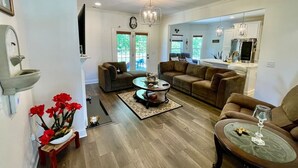 A spacious living room with a fireplace, a dining area, and a kitchen. - Immaculate 4 Bedroom with Pool Table (High Point)