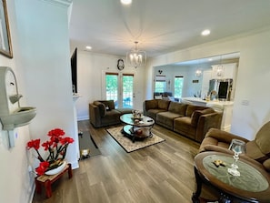 A spacious living room with a fireplace, a dining area, and a kitchen. - Immaculate 4 Bedroom with Pool Table (High Point)