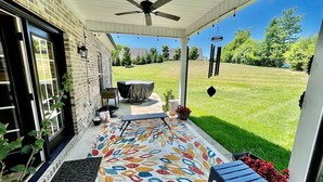 A covered porch with a ceiling fan, a table with a tablecloth, and a colorful rug. - Immaculate 4 Bedroom with Pool Table (High Point)