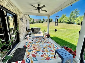 A covered porch with a ceiling fan, a table with a tablecloth, and a colorful rug. - Immaculate 4 Bedroom with Pool Table (High Point)