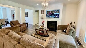 A living room with a fireplace, a television, and a sofa. - Immaculate 4 Bedroom with Pool Table (High Point)