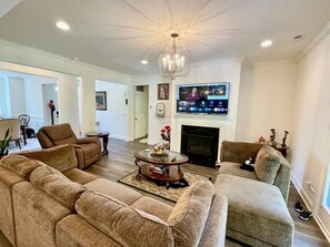 A living room with a fireplace, a television, and a sofa. - Immaculate 4 Bedroom with Pool Table (High Point)