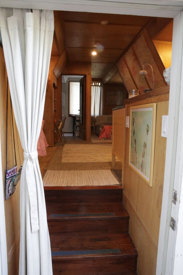 A wooden staircase leading to a living area with a couch, a chair, and a rug.