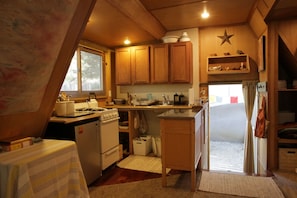 A compact kitchen with wooden cabinets, a stove, and a refrigerator.