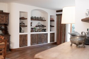 Ein Zimmer mit Holzböden, auf denen verschiedene Gegenstände ausgestellt sind, einem Holzschrank und einem Tisch mit einer Lampe.