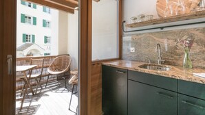 Cocina moderna con encimera de granito, pileta integrada y zona de comedor de madera con sillas.