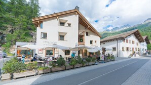 Un edificio con terraza al aire libre, un letrero que dice 'Chesa Survival' y montañas al fondo.