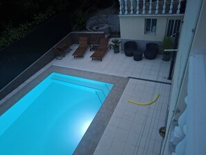 Une piscine avec des chaises longues attenantes et un petit espace patio.
