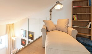 Ein modernes Schlafzimmer im Lofts-Stil mit Schlafsofa, Bücherregal und großem Spiegel.