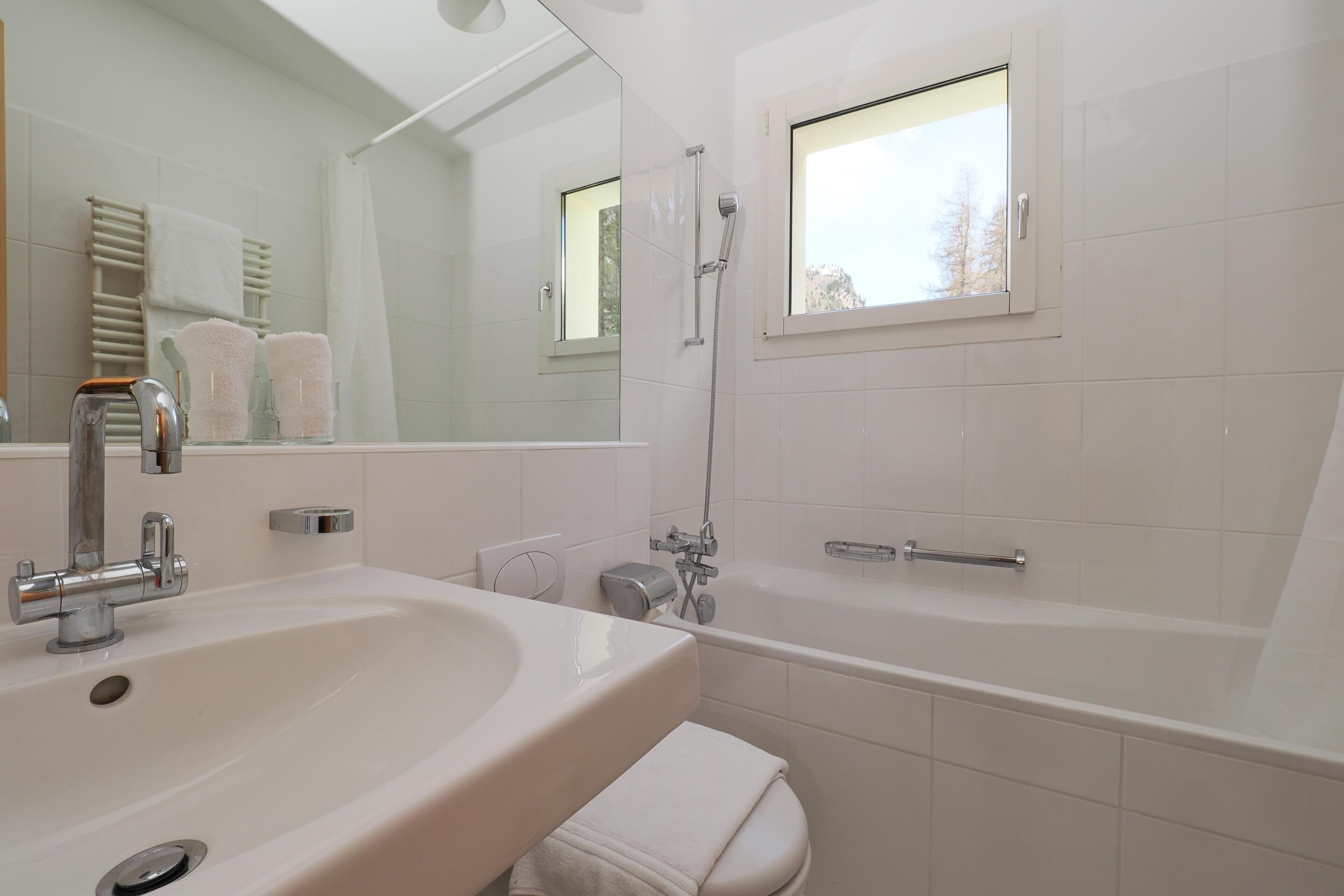 Un baño moderno con lavabo, espejo, ducha e inodoro.
