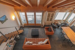 Ein geräumiger Wohnbereich mit Holzboden, einer Couch, einem Couchtisch und einem Esstisch.