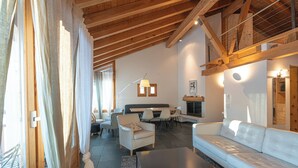 Ein gemütlicher Wohnbereich mit Sofa, Sesseln, einem Esstisch und einem Kamin.