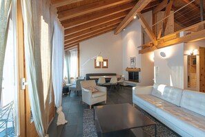 Ein gemütlicher Wohnbereich mit Sofa, Sesseln, einem Esstisch und einem Kamin.