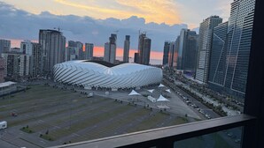 A modern stadium with a unique roof structure, surrounded by high-rise buildings and a clear sky. - Fantastico (Batumi)