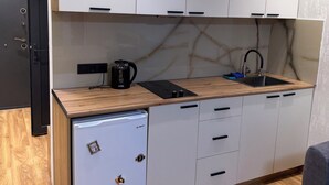 A compact kitchen with a built-in dishwasher, a sink, and a coffee maker. - Fantastico (Batumi)