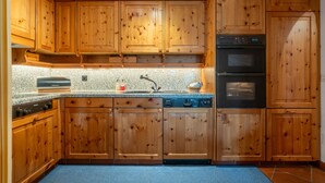 Une cuisine dotée de meubles en bois, d’un four encastré, d’un lave-vaisselle et de plans de travail en granit.