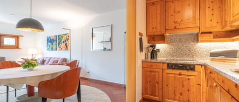 A modern kitchen with wooden cabinets, a granite countertop, and a dining area with a table and chairs.