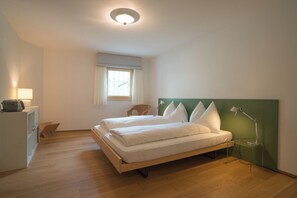 Ein Schlafzimmer mit Bett, Schreibtisch, Stuhl, Lampe und Fenster.