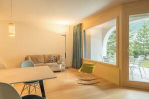 Ein modernes Wohnzimmer mit einer Couch, einem Esstisch und einem Schaukelstuhl.