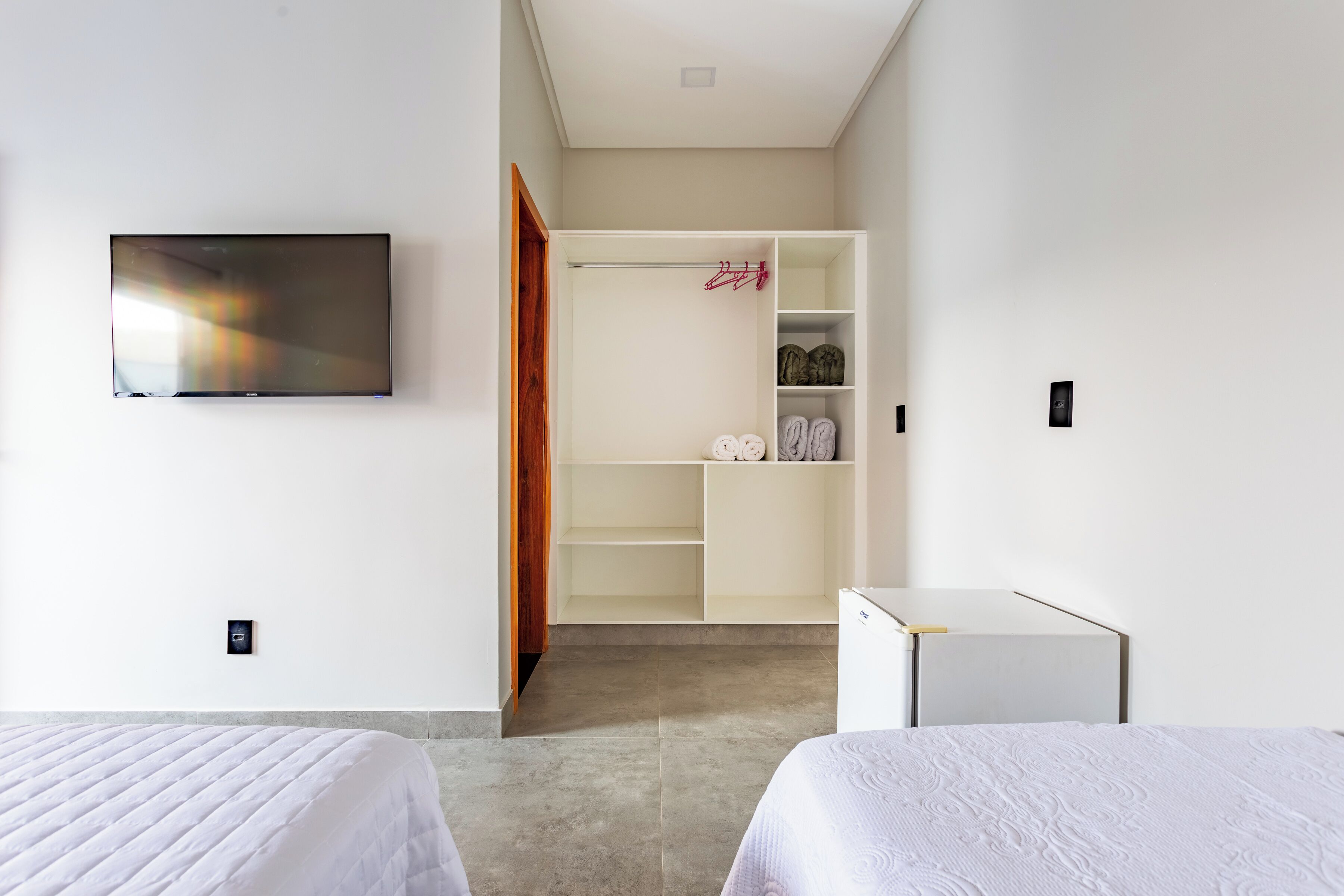 A hotel room with two beds, a TV, a wardrobe, and a small desk.