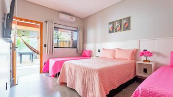 A bedroom with two beds, a TV, a window with curtains, and a hammock outside.