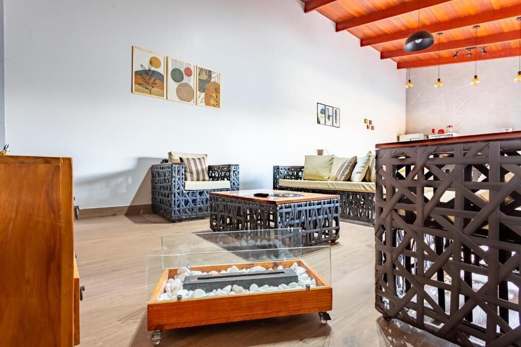 Un interior moderno con techo de madera, una mesa de centro de cristal y una zona de estar con cojines.
