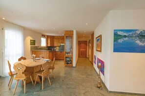 Ein Essbereich mit Holztisch und -stühlen, eine Küche mit Holzschränken und ein Flur mit einem Bild an der Wand.