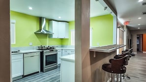 Une cuisine moderne avec des armoires blanches, une hotte de cuisinière en acier inoxydable et un four encastré.