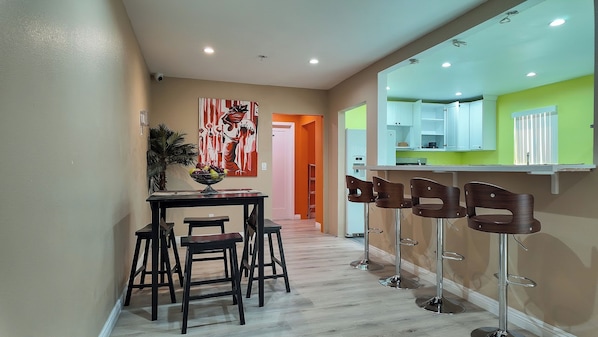 Une cuisine moderne avec un coin bar, des tabourets en bois et une table à manger avec des chaises.