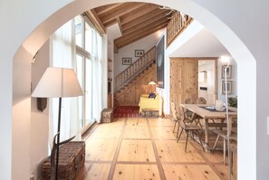 Ein geräumiges Zimmer mit Holzboden, einer Treppe, einem Essbereich und einem großen Fenster.
