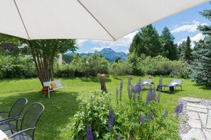Ein Garten mit einer Bank, Stühlen und einem Sonnenschirm.