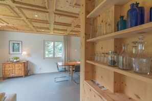Ein Zimmer mit Holzboden, einem Holzschrank mit Gläsern, einem Schreibtisch und einem Stuhl.