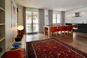 Eine moderne Küche mit Herd, ein Essbereich mit Tisch und Stühlen sowie ein großes Fenster mit Vorhängen.