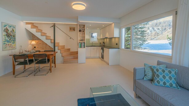 A modern interior with a staircase, dining area, kitchen, and a sofa with a view. - Chesa Lagrev 3 – Helle Duplexwohnung mit Garten (Sils/Segl Maria)
