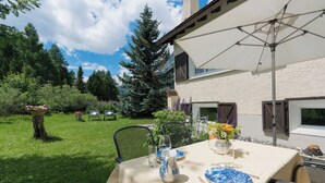 A table set outdoors with a tablecloth, plates, a pitcher, and chairs. - Chesa Lagrev 3 – Helle Duplexwohnung mit Garten (Sils/Segl Maria)